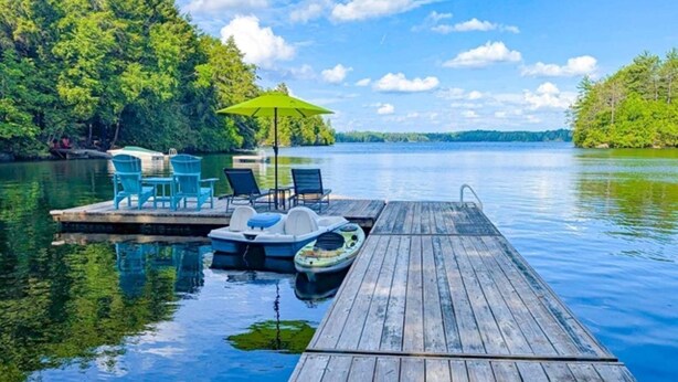 Un molo di legno si protende in un lago calmo, circondato da una rigogliosa vegetazione.