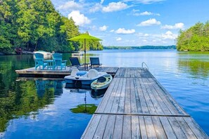 Une jetée en bois s’étendant sur un lac paisible, entourée d’une végétation luxuriante.