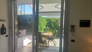 Eine Glastür, die auf eine Terrasse mit Tisch und Stühlen führt.