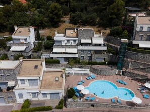 An aerial view of a residential area with modern houses, a swimming pool, and a small park.