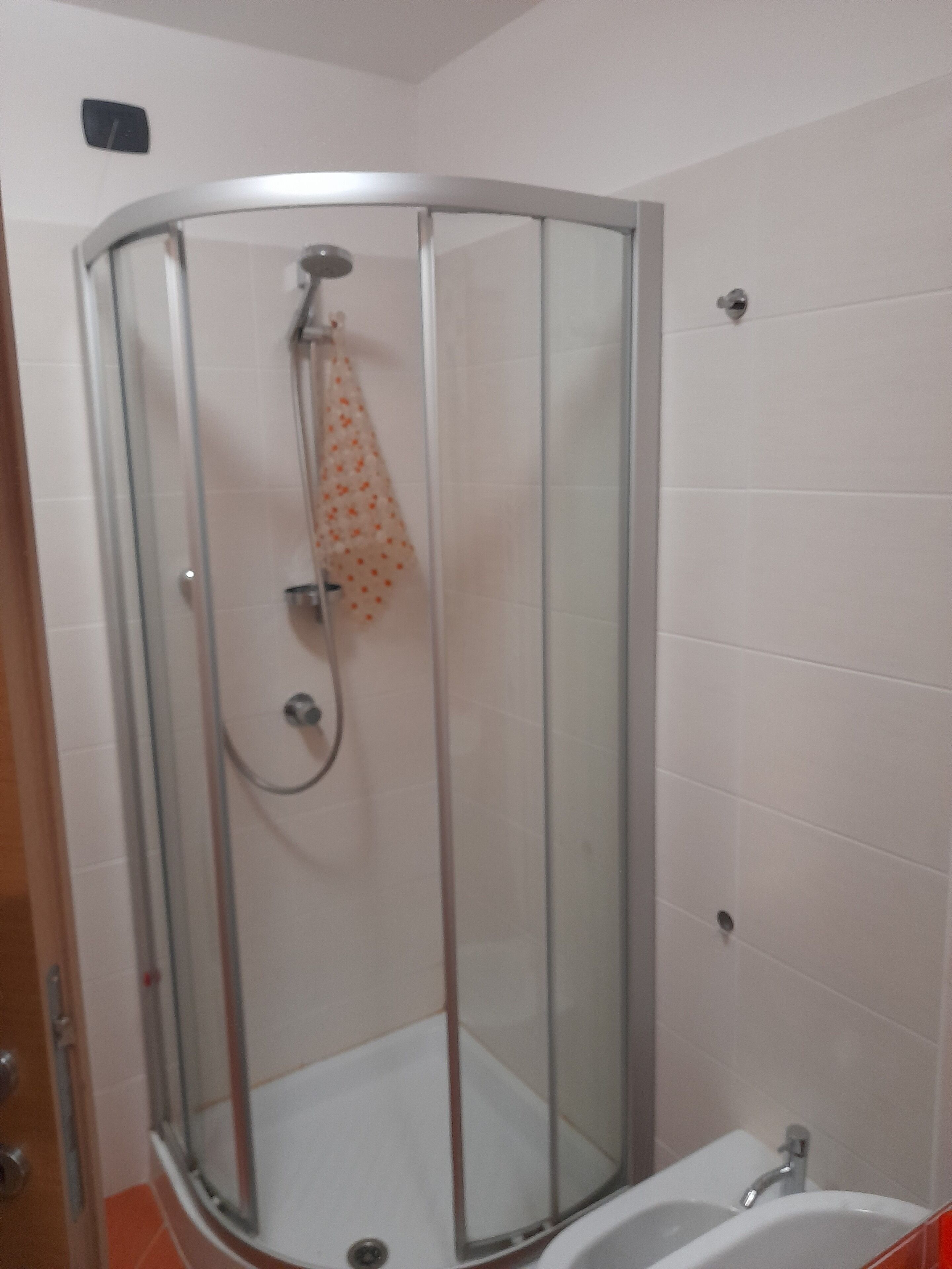 Een douchehoek met glazen deur en een handdouche.