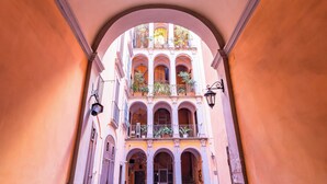 A narrow alleyway with a cobblestone path leading to a building with multiple balconies and a decorative ceiling. - Palazzo Loffredo by NapoliApartments (Naples)