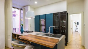A modern kitchen with a wooden island, stainless steel appliances, and teal cabinetry. - Palazzo Loffredo by NapoliApartments (Naples)