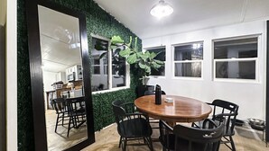 A dining area with a round wooden table, black chairs, and a large mirror on the wall. - Cozy 2-bedroom A-Frame near the Lake (Manhattan)