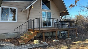 A two-story house with a wooden deck, a staircase, and a large window. - Cozy 2-bedroom A-Frame near the Lake (Manhattan)