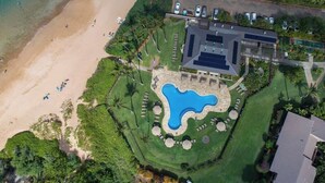 Vista aérea de un resort con una gran piscina, una playa y abundante vegetación.