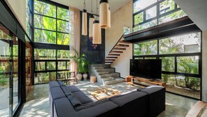 A modern living room with a large sectional sofa, a TV, and a staircase leading to an upper level.