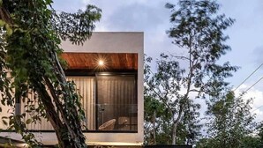 A modern house with a large window, a pool, and outdoor furniture.