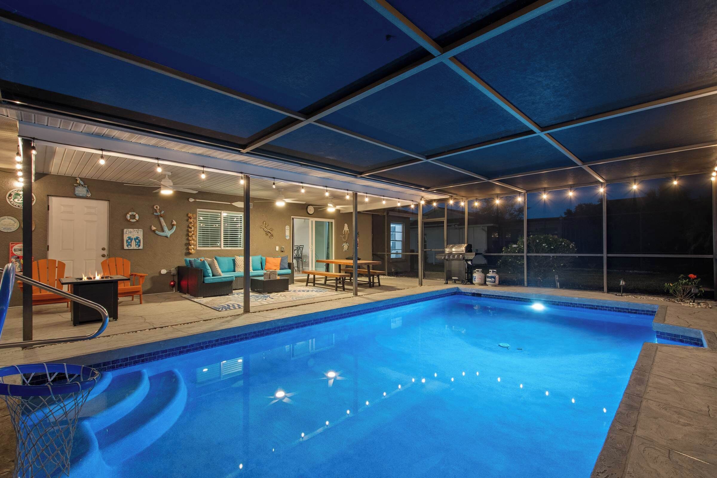 Ein Pool mit überdachter Terrasse, Sitzgelegenheiten im Freien und einem Grill.