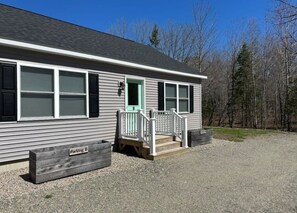 A single-story building with a front porch, a green door, and a sign indicating 'Parking B'.