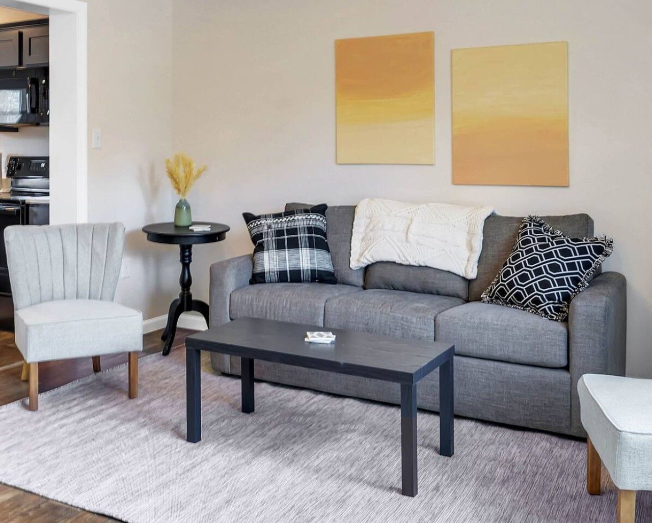 A living room with a grey sofa, a round coffee table, a grey armchair, and a small side table with a vase.