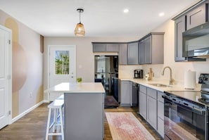 A modern kitchen with grey cabinets, a central island, and a built-in oven.