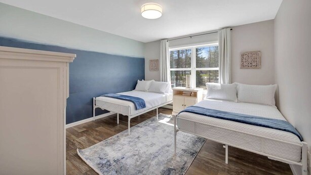 Ein Schlafzimmer mit zwei Betten, einem Fenster und einem Nachttisch.