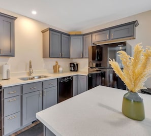 A modern kitchen with grey cabinets, a dishwasher, and a coffee maker.