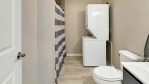 Ein kleines Badezimmer mit Toilette, Waschmaschine und Duschvorhang.