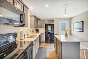 Una cucina moderna con elettrodomestici in acciaio inossidabile, forno integrato e un'isola grande con lavello.