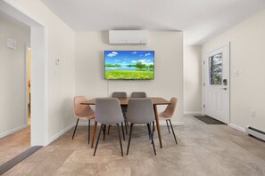 A dining area with a table and chairs, a mounted air conditioner, and a door with a window.