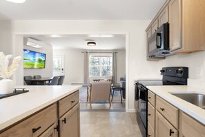A modern kitchen with a dining area, a TV, and a view of the outdoors.