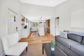 A modern living room with a grey sofa, a white armchair, and a coffee table with a plant.