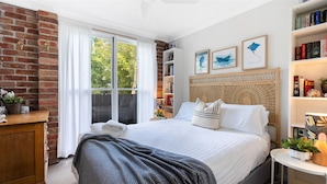 Een slaapkamer met een groot bed, een boekenkast en een raam met gordijnen.