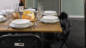Un comedor con una mesa de madera dispuesta para una comida, una botella de vino y una tabla de quesos.