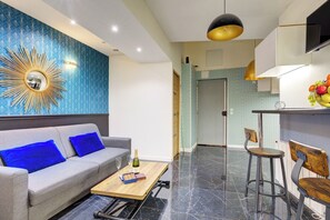 A modern living room with a grey sofa, a wooden coffee table, and a decorative mirror. - TheBlueStay 127 - Stunning Suite Near the Louvre (Paris)