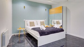 Un dormitorio moderno con una pared estampada, una cama con ropa de cama blanca, una mesita de noche y un espejo.