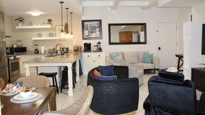 A modern living room with a dining area, kitchen, and a large window.