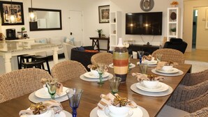 A dining area with a long table set for a meal, surrounded by wicker chairs.