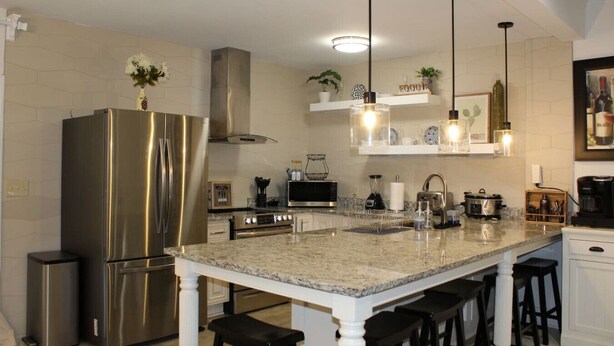 A modern kitchen with stainless steel appliances, granite countertops, and bar stools.