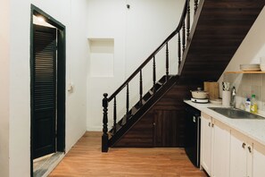 A kitchen with a wooden staircase, a sink, and a countertop with kitchenware. - Dusk House - 3BR house with city view (Hanoi)