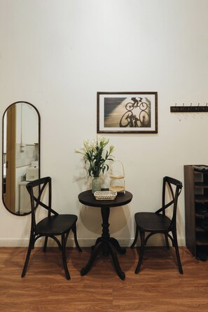 A room with a round table, two chairs, a mirror, a framed picture, a vase with flowers, and a shoe rack. - Dusk House - 3BR house with city view (Hanoi)