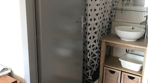 A bathroom with a shower curtain featuring a geometric pattern, a white sink, a mirror, and wicker baskets under the sink. - Studio in the mountains, 8 minutes from the slopes (Saint-Lary-Soulan)