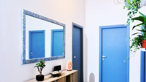 A hallway with a stone-tiled floor, a wooden console table with a potted plant, a mirror with a blue frame, and a blue door. - Close Cinecittà studios suitable for families and pets Metro 5 minutes walking (Roma)