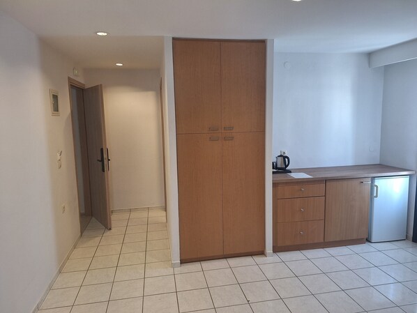 A kitchen with wooden cabinets, a countertop, and a small refrigerator. - SOHO BLUE city hotel (Hersonissos)