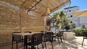 An outdoor seating area with a woven bamboo ceiling, black metal chairs, and a table. - SOHO BLUE city hotel (Hersonissos)