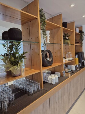 Un área de recepción con estanterías de madera, vitrinas de vidrio y diversos objetos, como plantas, tazas y cristalería.