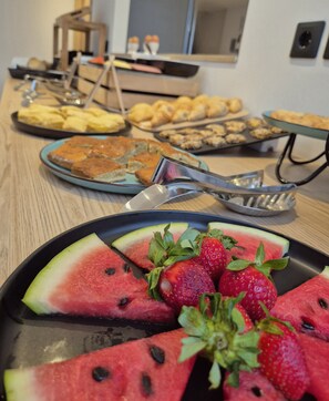 A buffet table with various food items including watermelon slices, strawberries, and pastries. - SOHO BLUE city hotel (Hersonissos)