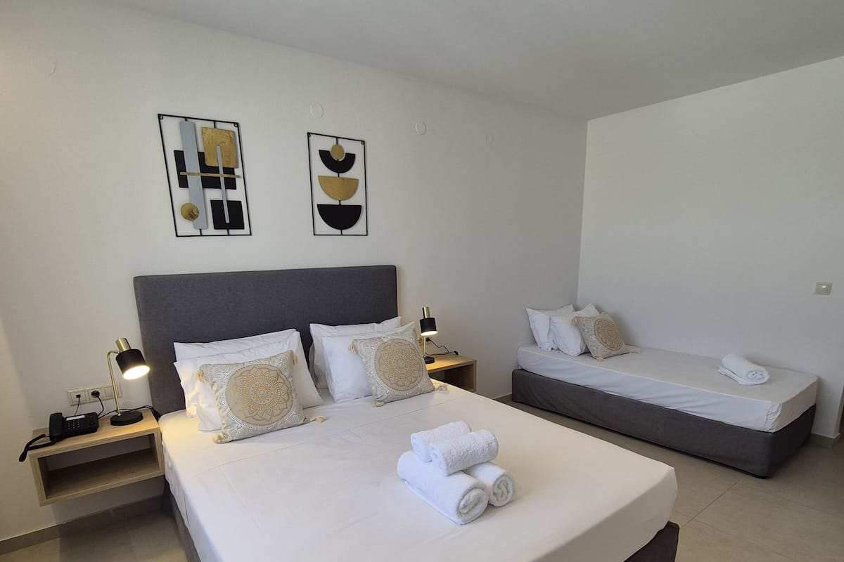 A modern hotel room with a large bed, a smaller bed, and a nightstand with a lamp.