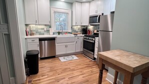 A modern kitchen with white cabinets, a stainless steel refrigerator, and a wooden dining table.