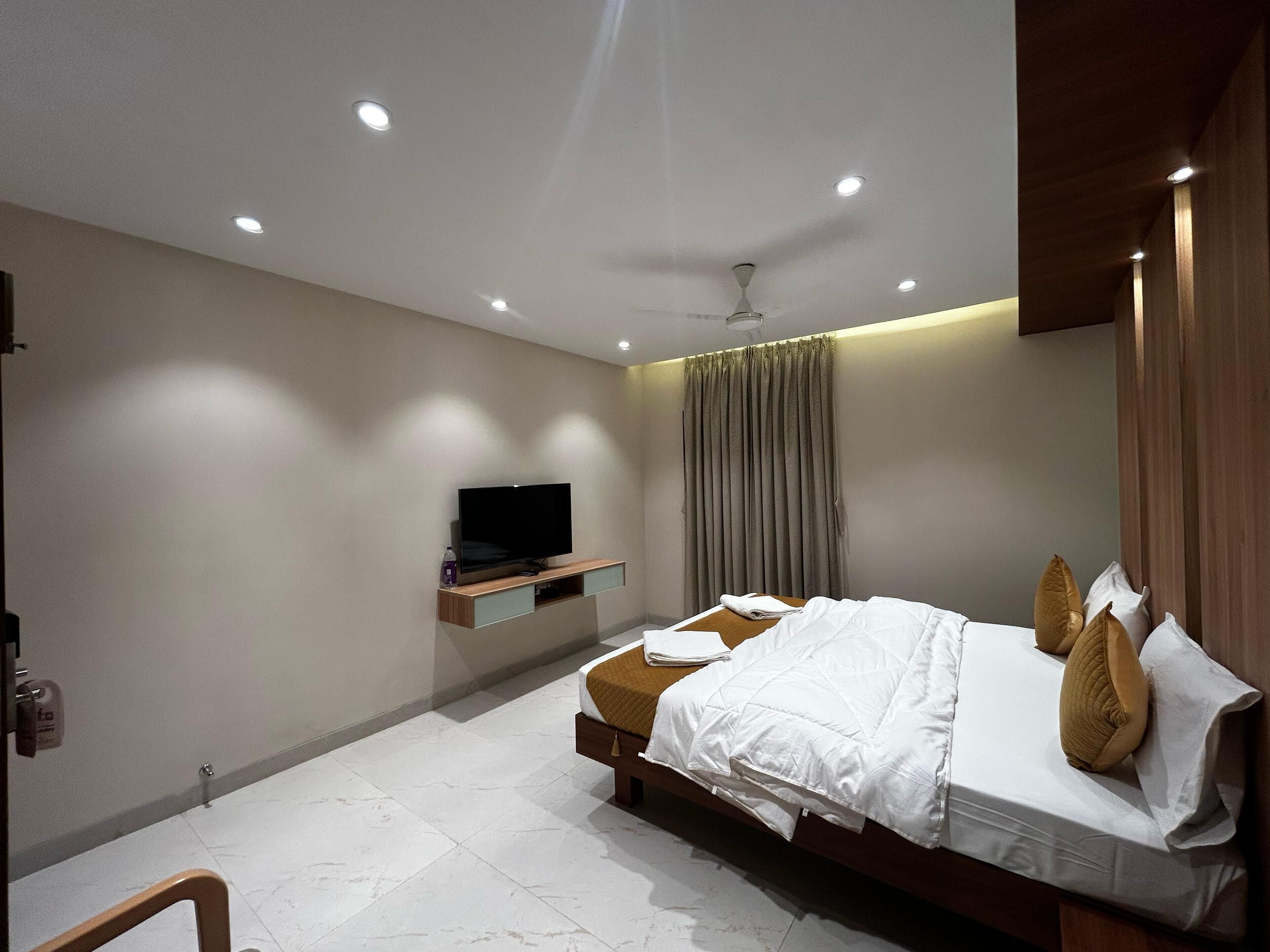 Ein modernes Schlafzimmer mit einem Bett, einem an der Wand befestigten Fernseher und einem Deckenventilator.