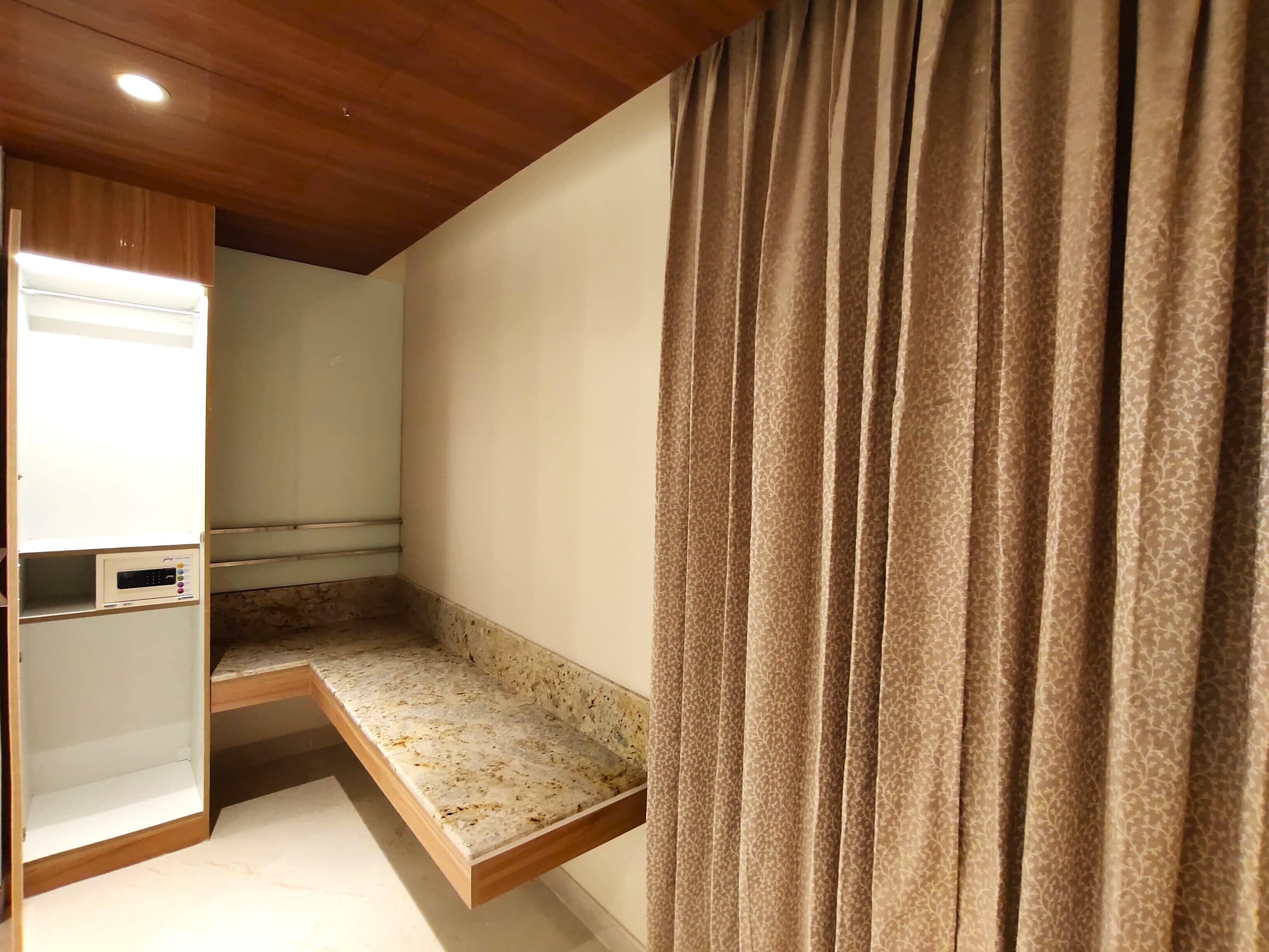 Una habitación con un banco empotrado, un panel de control y una cortina.