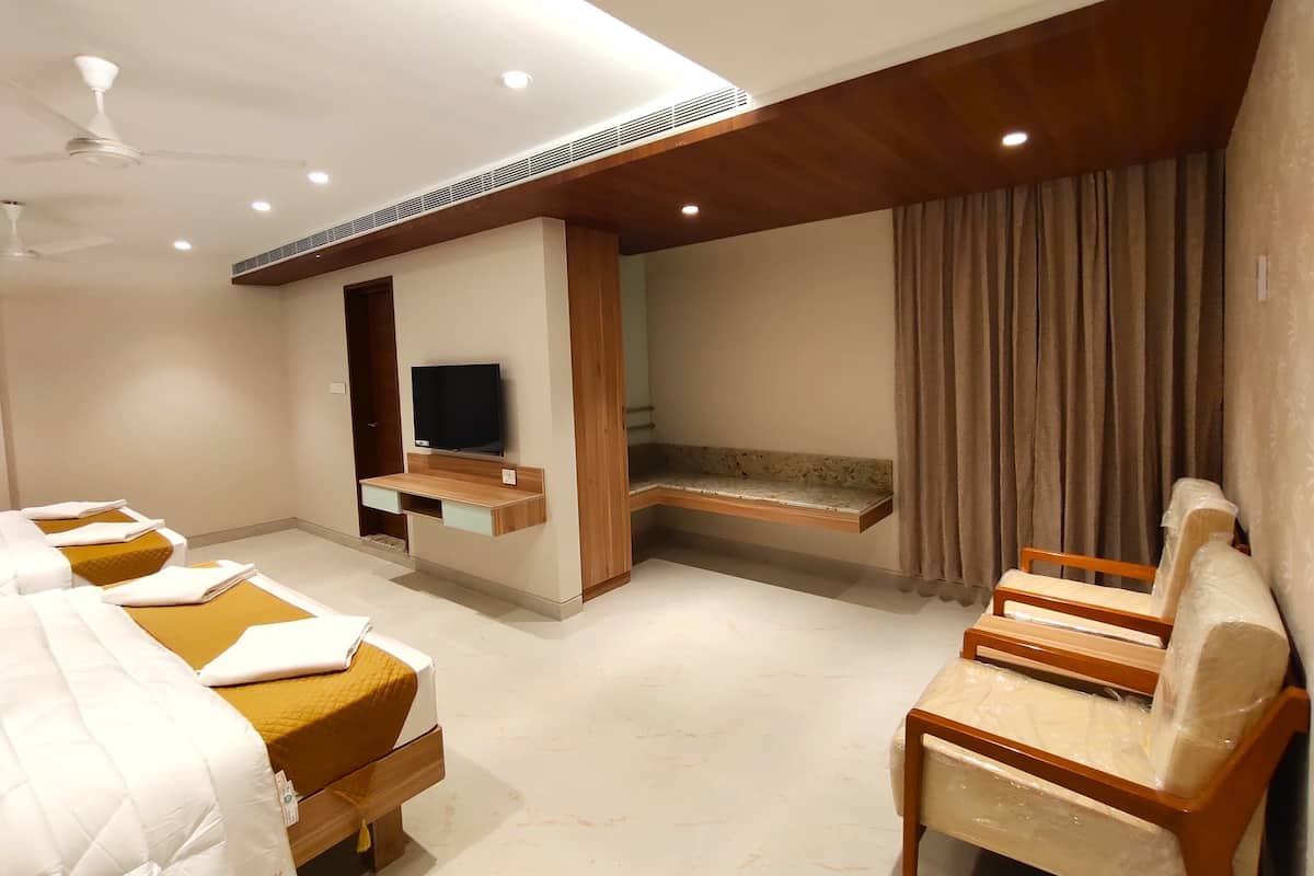 Une chambre d’hôtel avec deux lits, une télévision, un banc en bois et une fenêtre avec des rideaux.