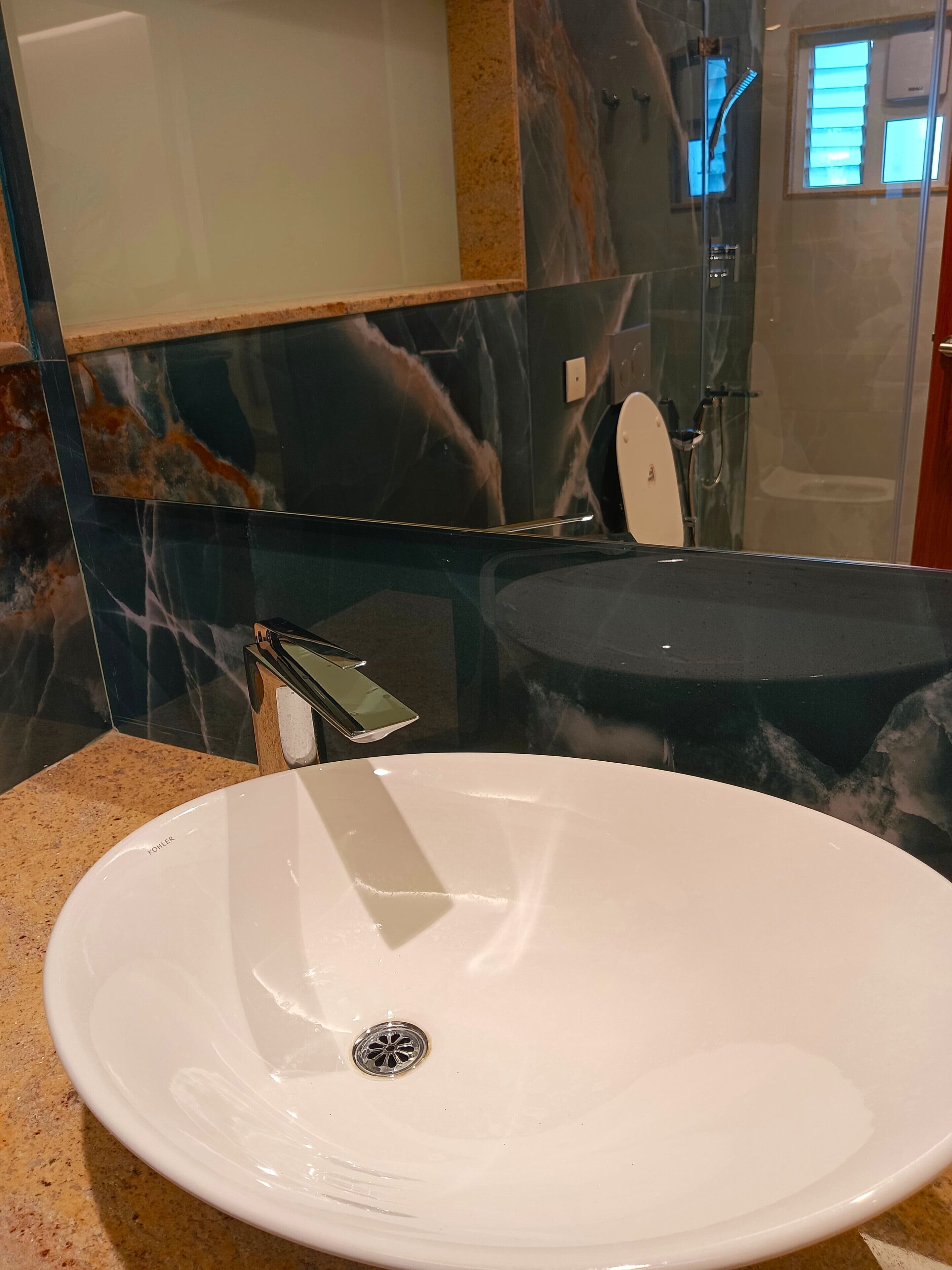 Ein Badezimmer mit einem weißen Waschbecken, einem Spiegel und einer Duschkabine.