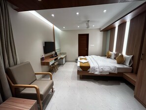 A modern hotel room with a bed, a desk, a chair, a television, and a wardrobe. - THE PARADISE KINGDOM (Kanchipuram)