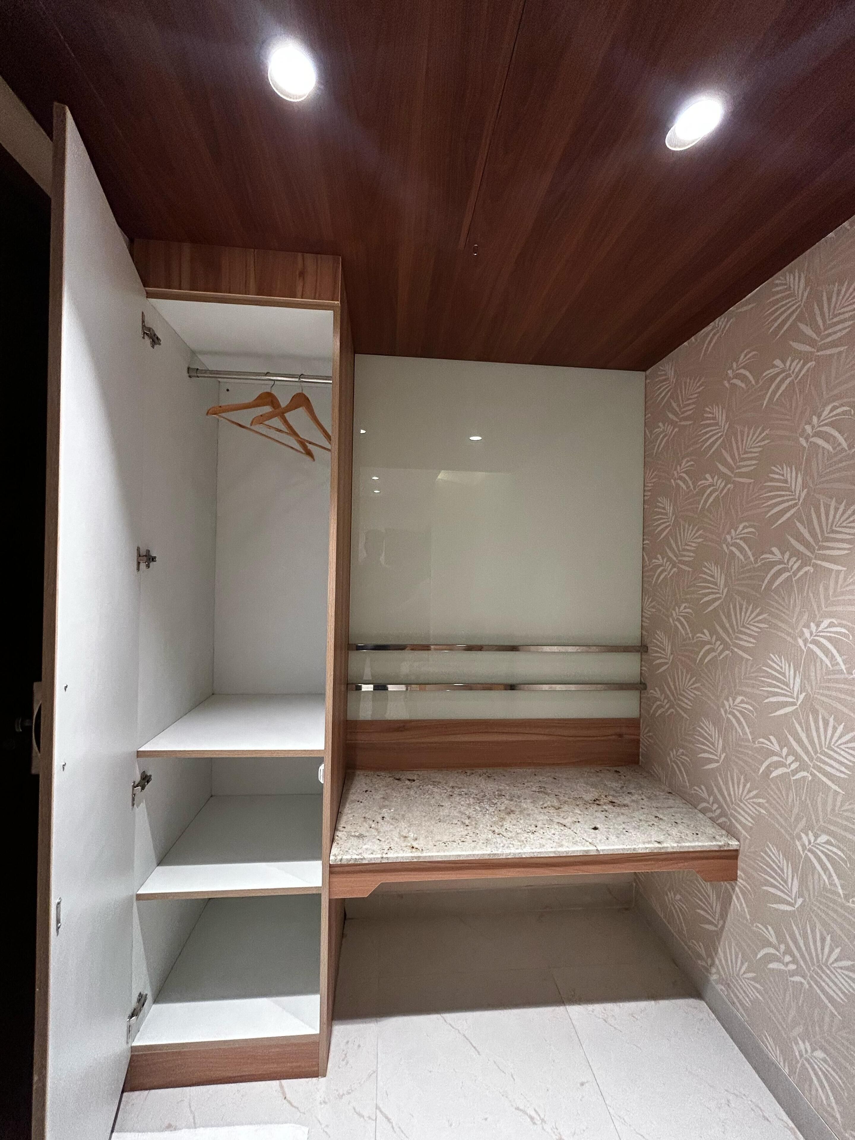 A walk-in closet with open shelving, a hanging rod, and a bench.