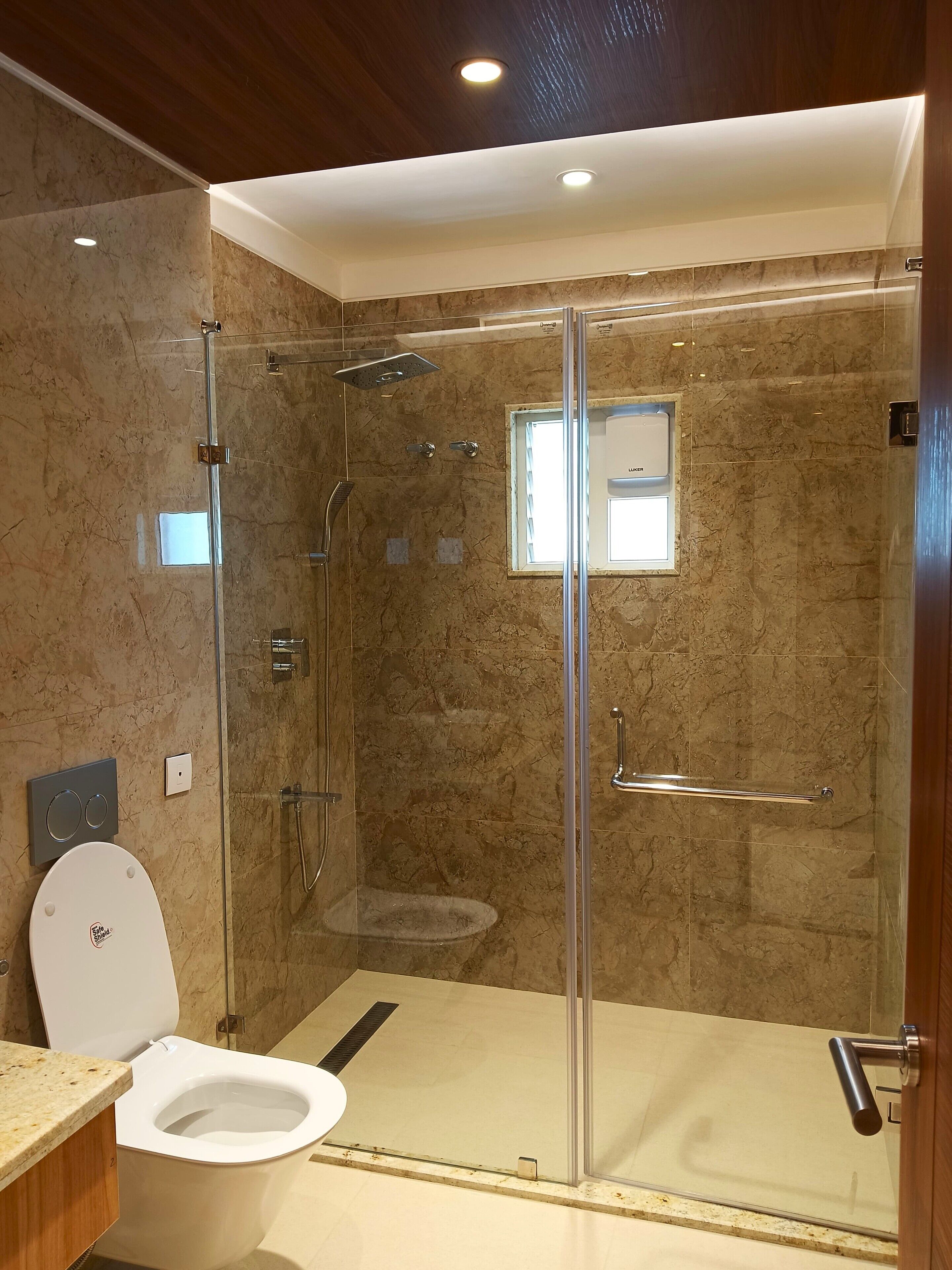 Une salle de bain moderne dotée d’une douche à parois de verre, de toilettes et d’un lavabo.