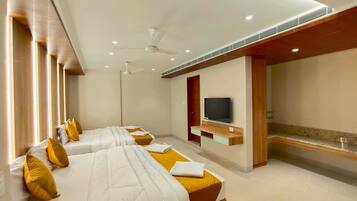 A hotel room with two beds, a TV, ceiling fans, and recessed lighting.