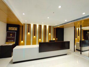 A modern reception desk with a glass partition, a logo on the wall, and a sign for 'The Paradise Kingdom Luxury Stay'. - THE PARADISE KINGDOM (Kanchipuram)
