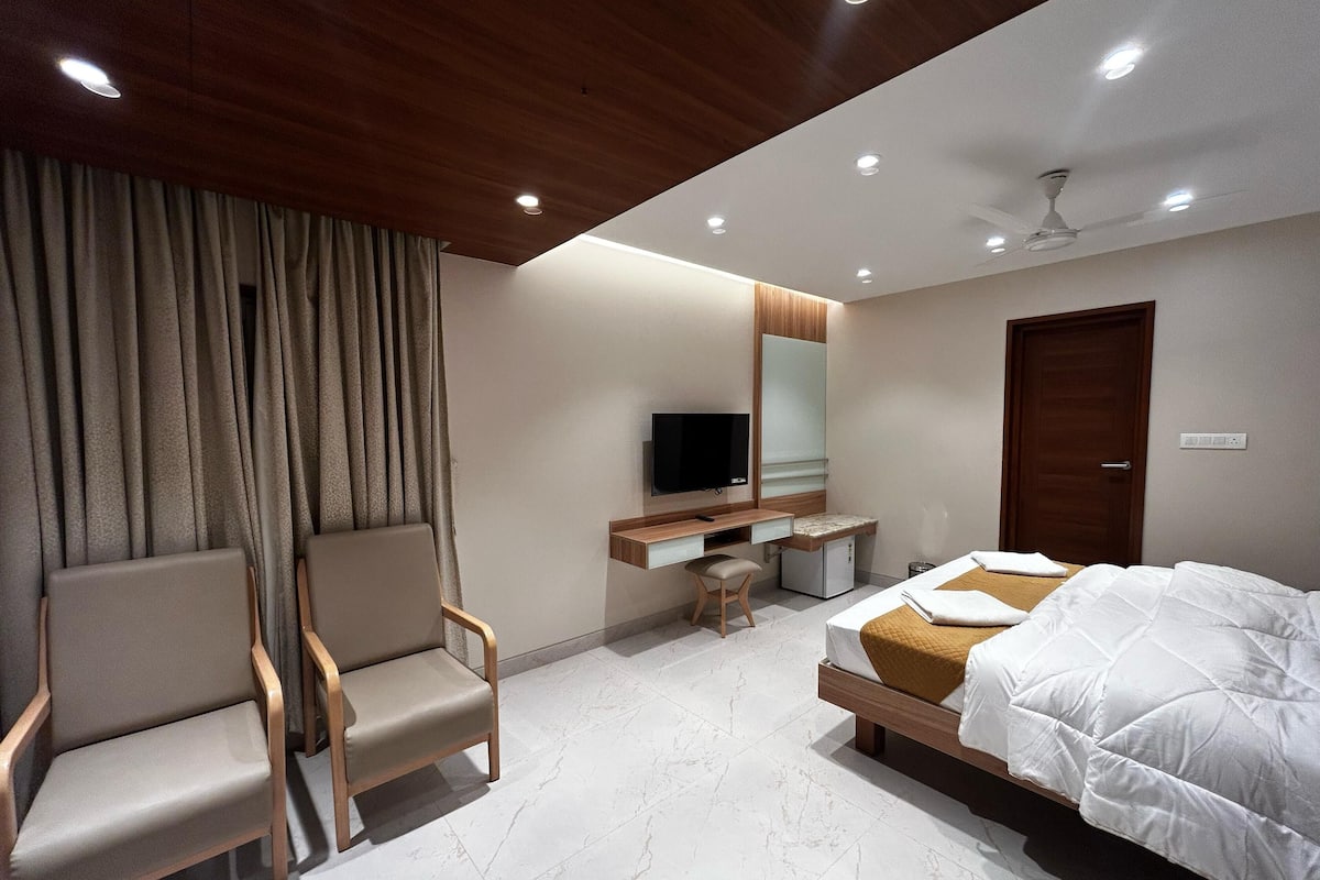 Une chambre d’hôtel comprenant un lit, un bureau avec une chaise, une télévision et une armoire.